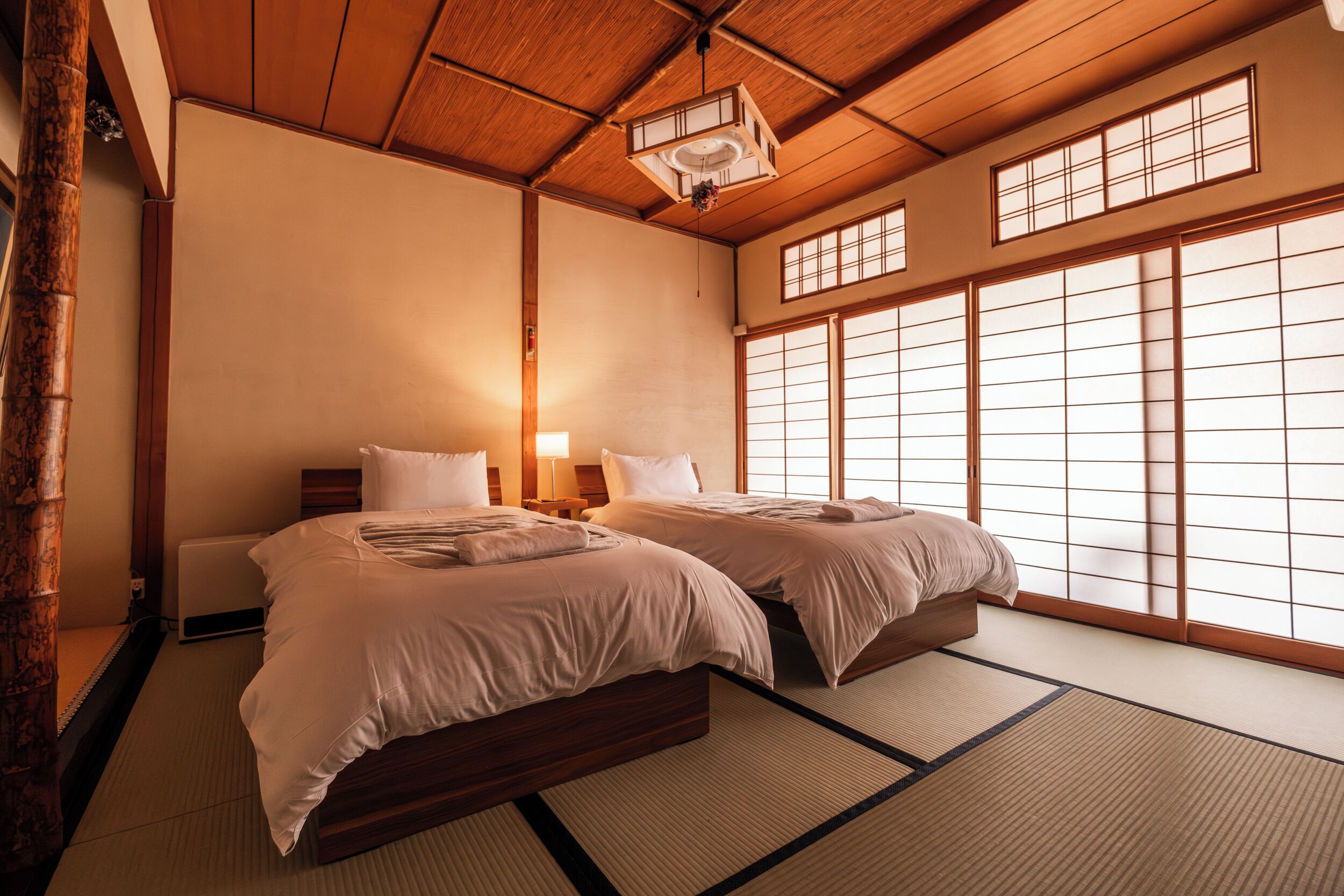 A traditional Japanese-style room with tatami flooring, a wooden ceiling, and sliding shoji doors.