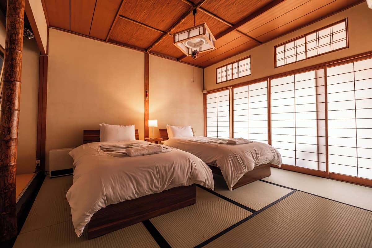 A traditional Japanese-style room with tatami flooring, a wooden ceiling, and sliding shoji doors.