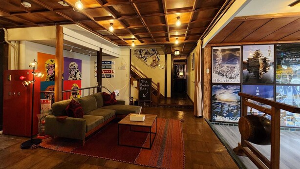 Un interior acogedor con techo de madera, un sofá, una mesa de centro y vistas de una edificación japonesa tradicional.