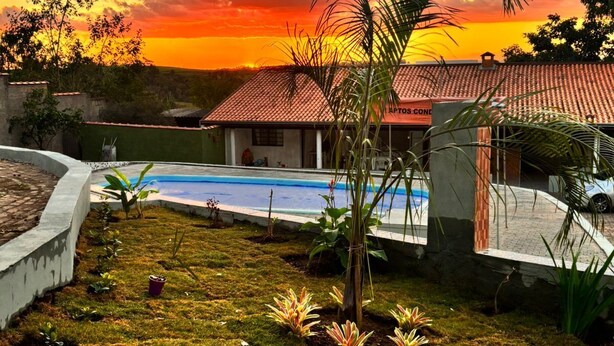 A residential property with a swimming pool, a red-tiled roof, and a garden with various plants. - Cozy country house surrounded by nature, with a beautiful sunset view. (Piracicaba)