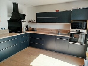 A modern kitchen with dark cabinetry, a built-in oven, and a microwave. - Quiet, single-storey family villa between sea, lake and mountains. (Servian)