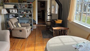 A cozy living room with a fireplace, a bookshelf, a comfortable armchair, and a dining table. - Charming 1-bedroom apartment in Worcester, private swimming hole. (Worcester)