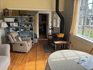 A cozy living room with a fireplace, a bookshelf, a comfortable armchair, and a dining table. - Charming 1-bedroom apartment in Worcester, private swimming hole. (Worcester)