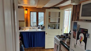 A kitchen with wooden floors, a stove, a refrigerator, and a window with a view of the outside. - Charming 1-bedroom apartment in Worcester, private swimming hole. (Worcester)