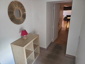 A hallway with a wooden console table, a red lamp, and a sunburst mirror on the wall.