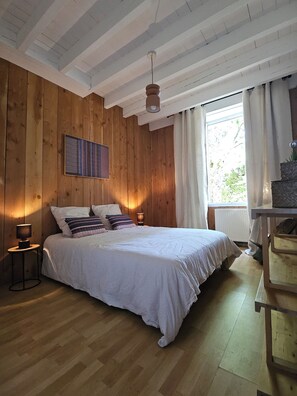 A bedroom with a wooden ceiling, a bed with white bedding, a nightstand with a lamp, and a window with curtains. - Charentais country house surrounded by vineyards with a heated pool (Mosnac)