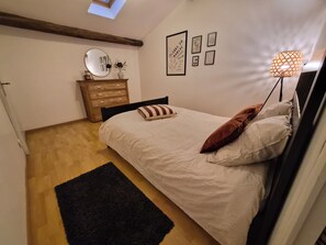 A bedroom with a bed, a dresser, a mirror, and wall art.