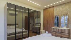A modern bedroom with a bed, a glass partition, a vanity with a mirror, and a wooden panel wall. - Alsawah|Luxury 6BR Villa with Private Pool (Sheikh Zayed City)