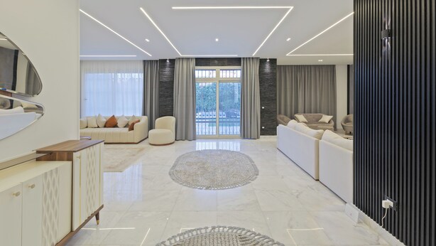 A modern living room with a sofa, a coffee table, and a TV. - Alsawah|Luxury 6BR Villa with Private Pool (Sheikh Zayed City)