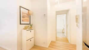 A hallway with a white cabinet, a framed picture, and a door leading to a bathroom.