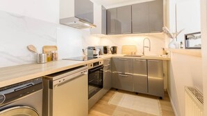 A compact kitchen with stainless steel appliances, a built-in oven, and a dishwasher.