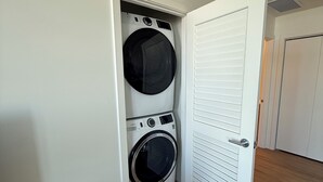 Un lavadero con lavadora y secadora, una puerta blanca y suelo de madera.