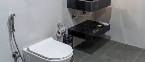 Un baño moderno con inodoro, lavabo con espejo y secador de pelo en la pared.