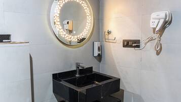 A bathroom with a round mirror, a hairdryer, and a soap dispenser.