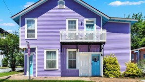 Ein zweistöckiges Haus mit Balkon, einer blauen Tür und einem Stoppschild.