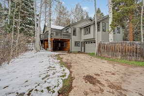 A two-story house with a wooden deck, a covered entryway, and a fenced yard.