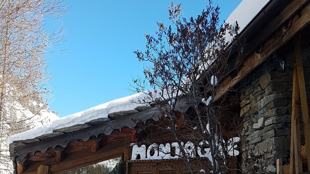 Un edifici de fusta rústic amb un teulat cobert de neu i un cartell que diu 'MOMENT'.