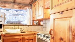 Una cuina de fusta amb armaris, un rentatges, una cuina i una finestra amb vistes.