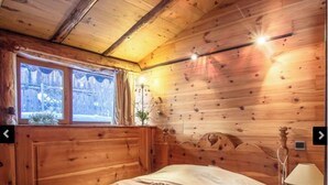 Una habitació de fusta amb un llit, una finestra i una làmpada.