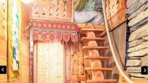 Un interior de fusta amb una escala de caragol, un paviment de rajoles i una porta de fusta decorativa.