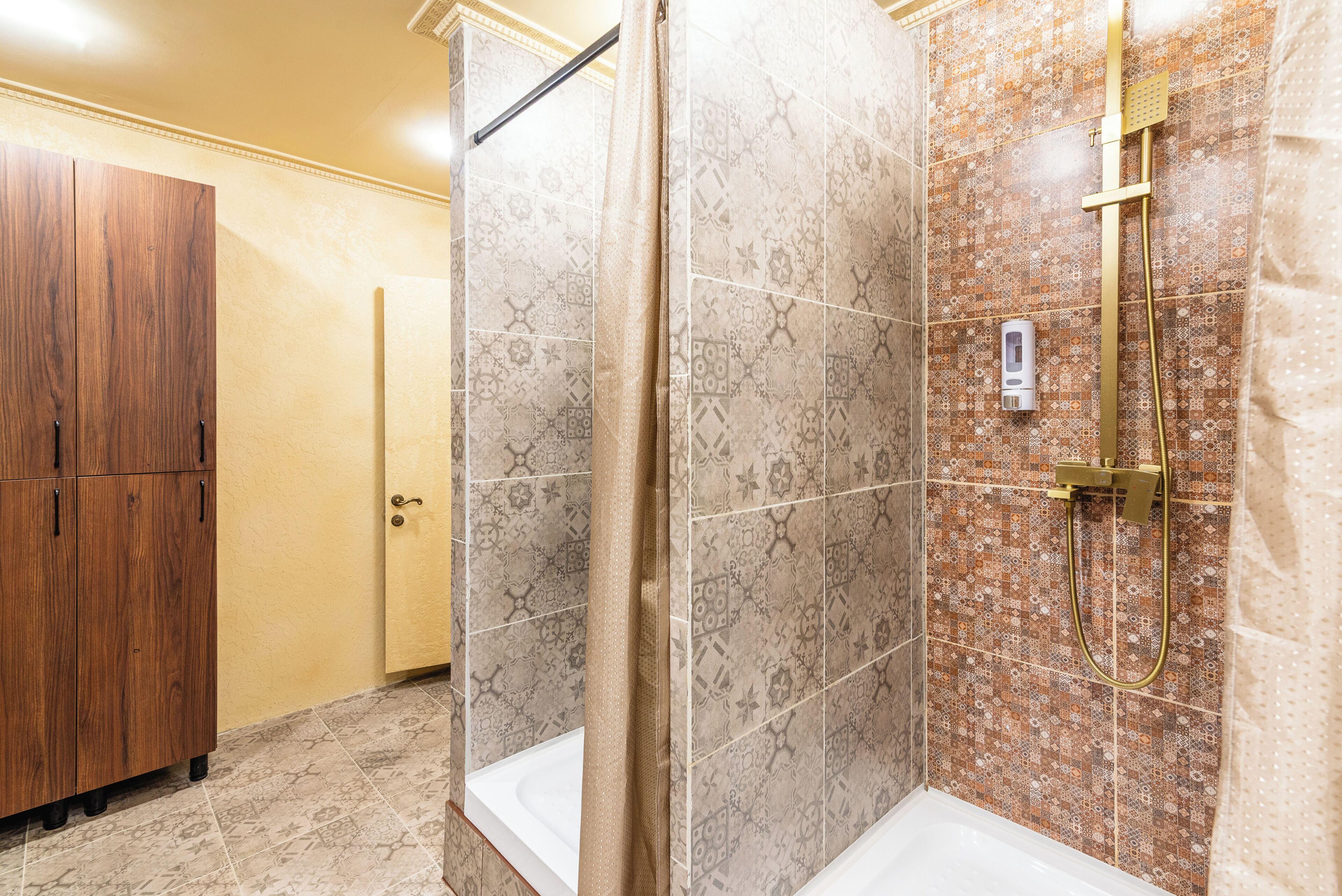 Une salle de bain avec une douche, une armoire en bois et des carreaux décorés.