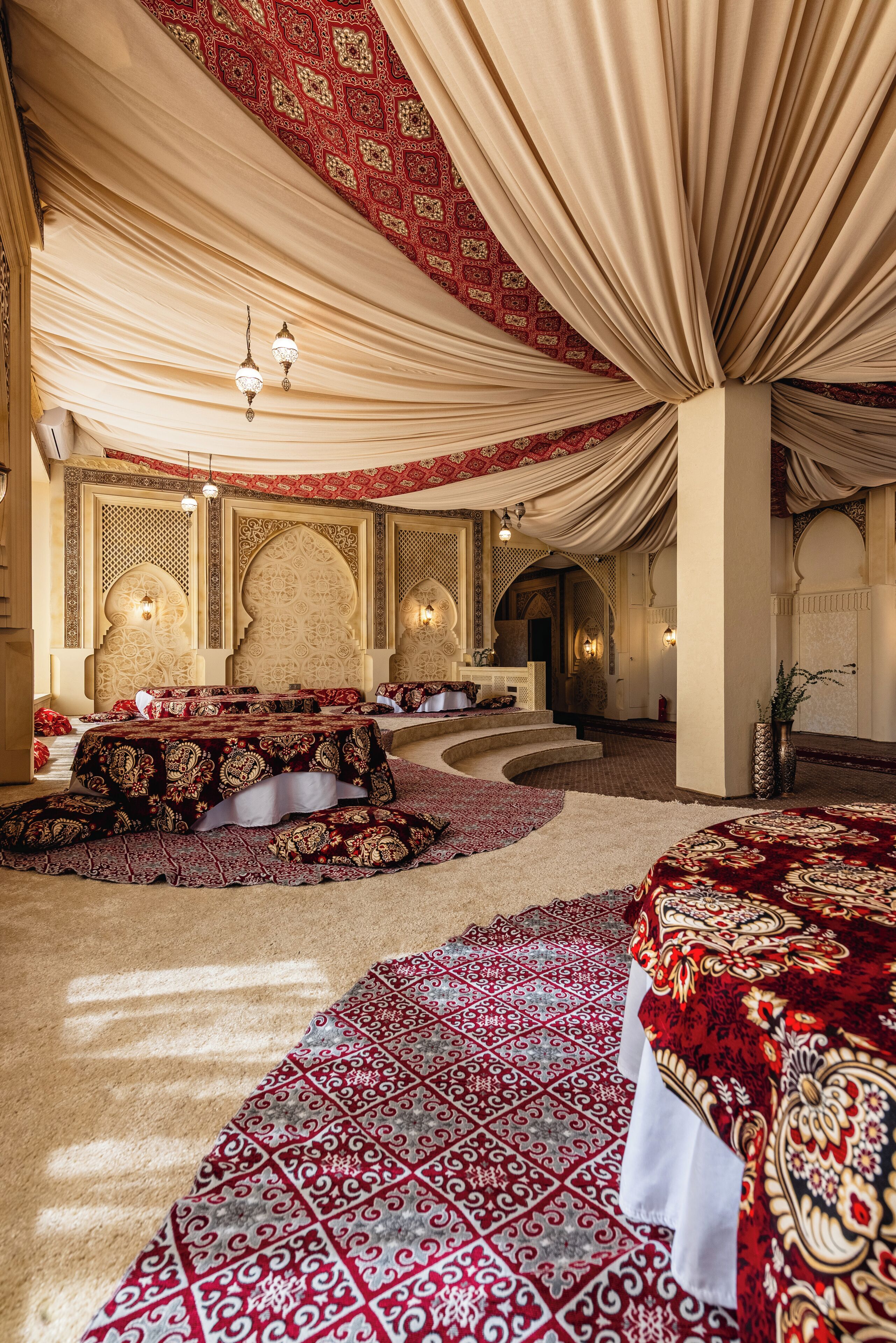 A luxurious room with a large bed, a seating area, and a staircase.