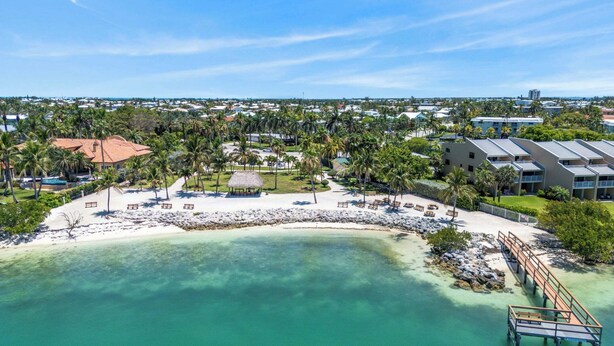 A resort with a beach, palm trees, and a water view. - The perfect tropical sanctuary with turquoise waters and steps from the beach. (Key Colony Beach)
