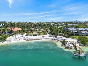 Un complexe hôtelier doté d’une plage, de palmiers et offrant une vue sur l’eau.