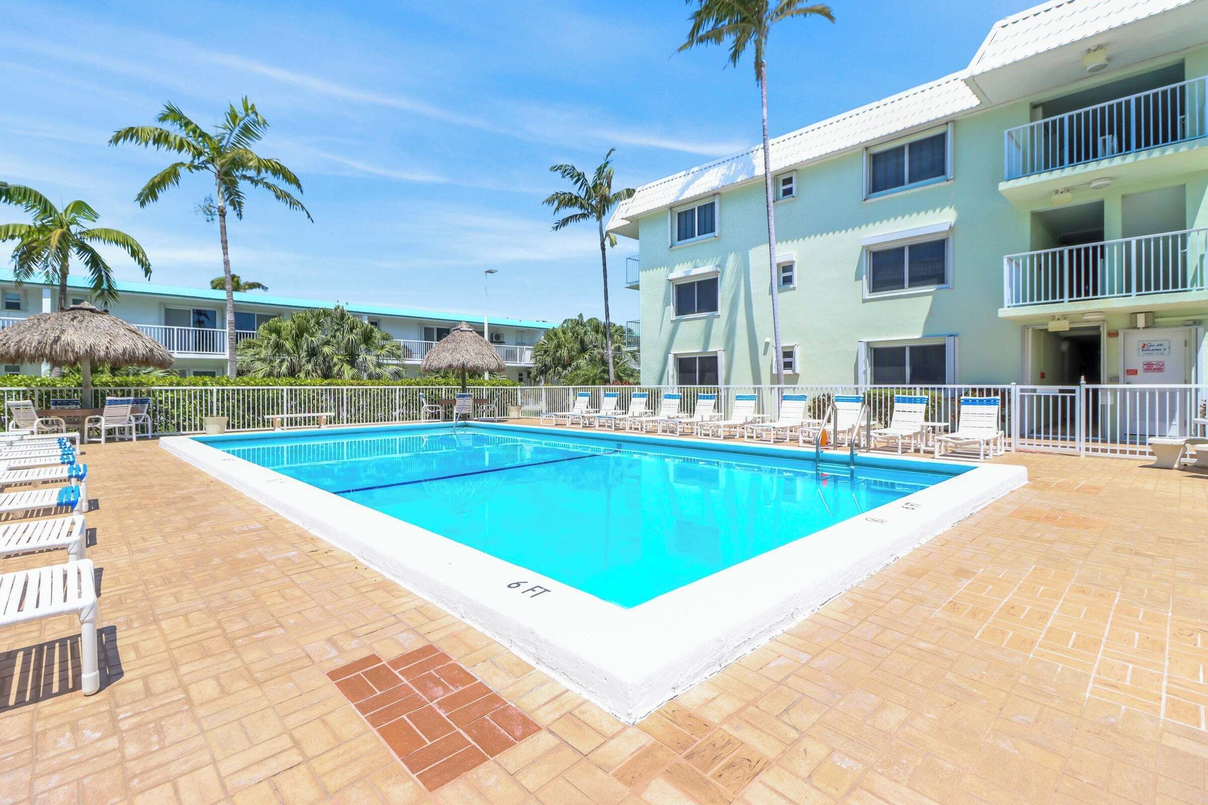 Une piscine avec des chaises longues et des palmiers.