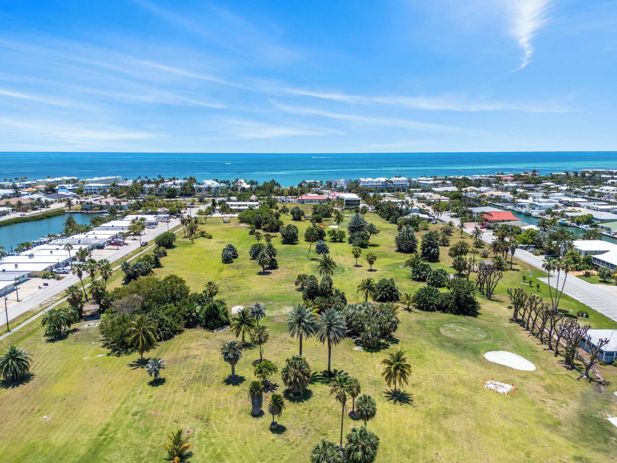 An aerial view of a coastal area with a marina, green spaces, and buildings.