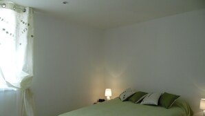 Ein Schlafzimmer mit einem Bett, zwei Nachttischen, einem Fenster mit Vorhängen.