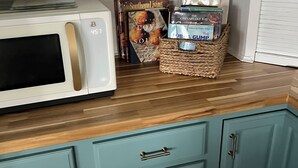Een keuken met een magnetron, een mand vol boeken en turquoise kastjes.