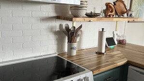 Een keuken met een witte baksteenmuur, houten planken, een witte kookplaat en een blauwgroene vaas.