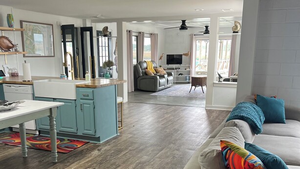 Een ruime woonkamer met een bank, een eettafel en een keukenhoek.