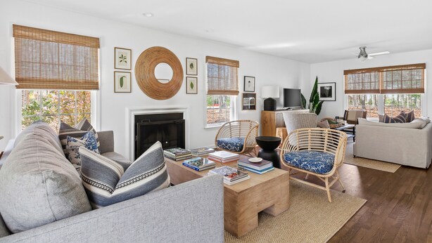 A living room with a fireplace, wicker chairs, a sofa, and books. - Classic 4-bedroom Home in East Hampton, Minutes from Town (East Hampton)