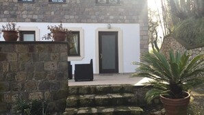 A stone building with a white facade, a black door, and steps leading to a black chair.