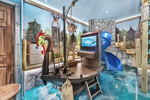 Ein Zimmer mit einer Rutsche, einem Fernseher und einem Wandbild eines Waldes.