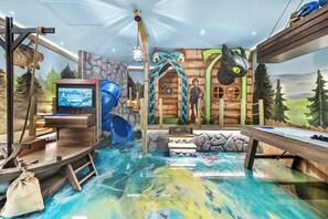 Una habitación con piscina, televisor y tobogán.