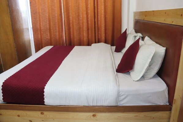 A bed with a wooden headboard, white bedding, and red accents. - hotel tourist home by palak hospitality (Mussoorie)