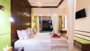 A hotel room with a bed, bedside table, TV, and a view of a pool. - Nauli Villas Sanur (Denpasar)