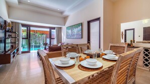 A dining area with a table set for four, wooden chairs, and a view of the outdoors. - Nauli Villas Sanur (Denpasar)