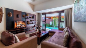 A modern living room with a fireplace, leather sofas, a coffee table, and a bookshelf. - Nauli Villas Sanur (Denpasar)