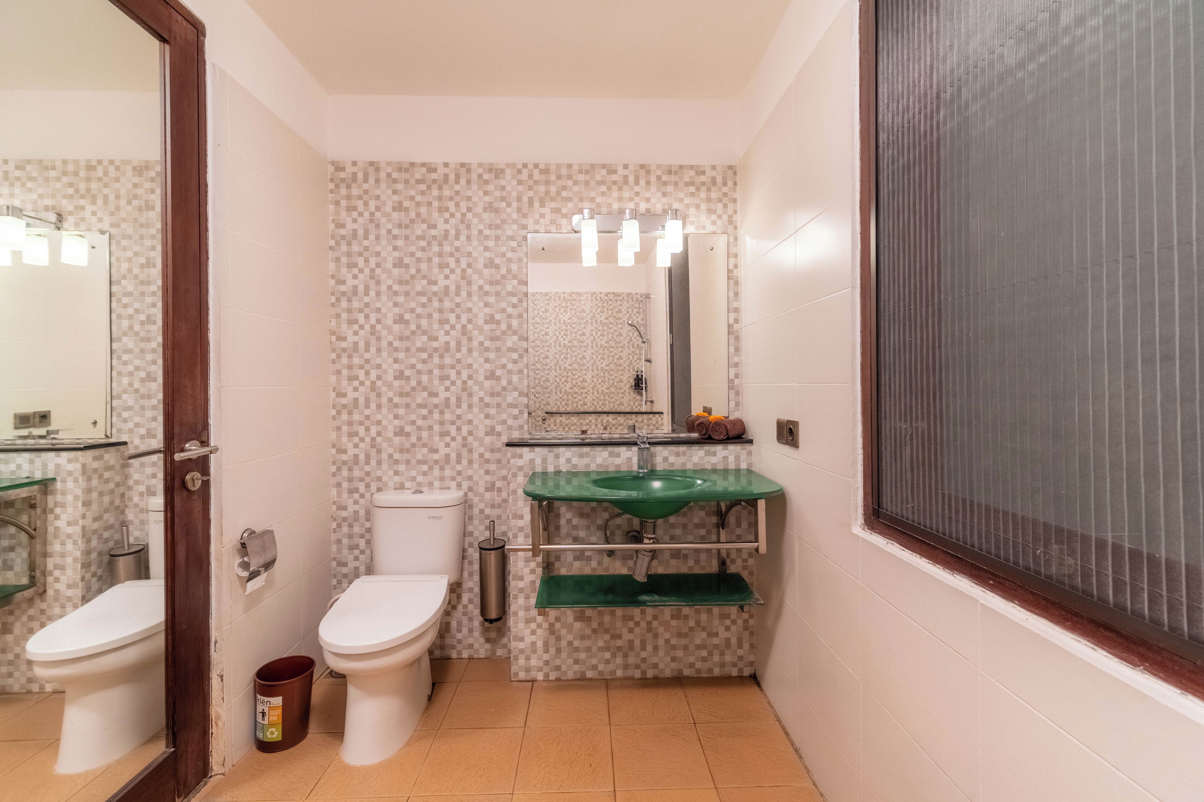 A bathroom with a toilet, sink, and mirror.