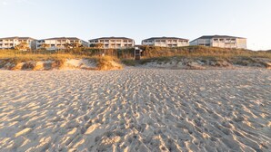 Ett hotell vid stranden med flera byggnader, en sandstrand och sanddyner.