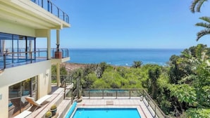 Ein zweistöckiges Gebäude mit Pool mit Blick auf Strand und Meer.