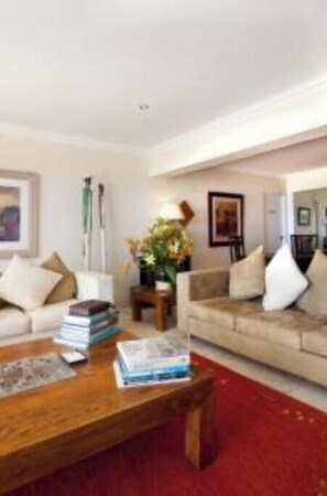 A living room with two sofas, a coffee table, and a red carpet. - Long-standing luxury guesthouse overlooking the Atlantic Ocean and Lion's Head. (Cape Town)