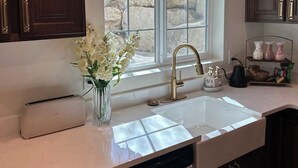 A kitchen with a window, a toaster, a vase with flowers, and a sink.