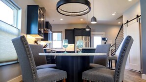 A modern kitchen with a central island, dark cabinetry, and a chandelier. - The Cornice- Sleeps 8 - AC - Pet Friendly - Modern Townhome (Red Lodge)