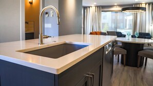 A modern kitchen with a large island, a built-in sink, and a dining area with a round table and chairs. - The Cornice- Sleeps 8 - AC - Pet Friendly - Modern Townhome (Red Lodge)