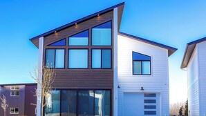A modern two-story house with a garage, large windows, and a sloped roof. - The Cornice- Sleeps 8 - AC - Pet Friendly - Modern Townhome (Red Lodge)